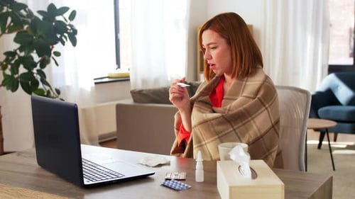 Woman Under Blanket Consults Doctor Using Laptop