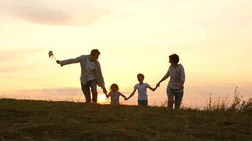 Happy Family Running on Hilltop at Sunset