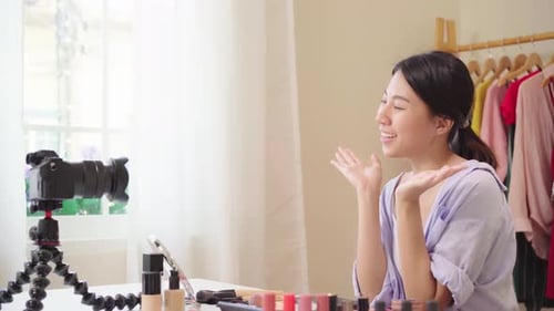 La bloguera de belleza presenta cosméticos de belleza sentada frente a la cámara frontal para grabar un vídeo de una mujer asiática.