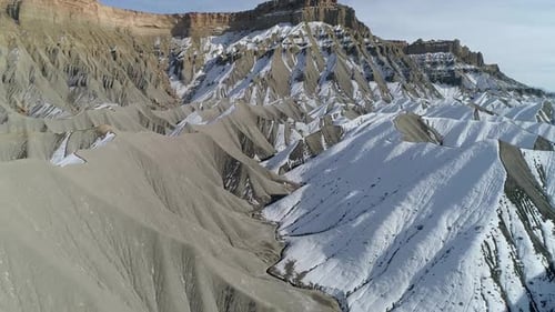 Flying low through desert dunes half covered in snow