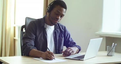 Young Adult Taking Notes While Using Computer