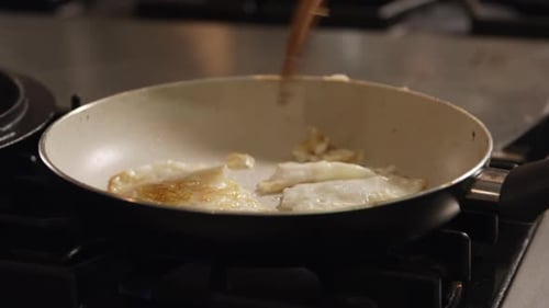 Cooking Eggs in Frying Pan with Wood Utensil