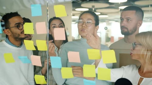 Creative Team Collaborates Using Sticky Notes in Office