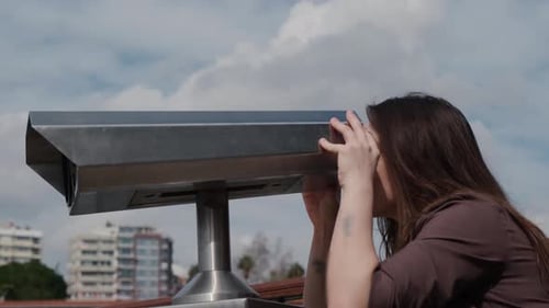 Woman Looks Through Telescope in City on Cloudy Day