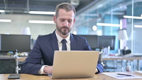 Ambitious Businessman Working on Laptop on Office Desk