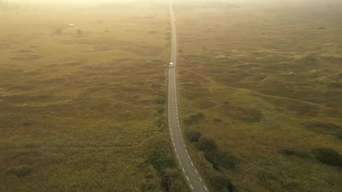 Vue Drone de la route au milieu des champs verts avec un ciel lumineux