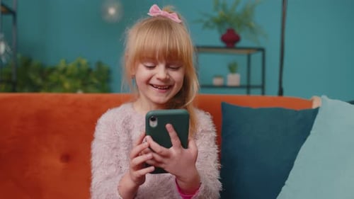 Girl Smiles Using Phone Indoors on Couch