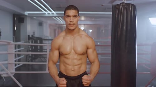 Kickboxen, Athletic Man Fighter trainiert im Boxstudio, ein muskulöser Mann nimmt eine Kampfhaltung ein.