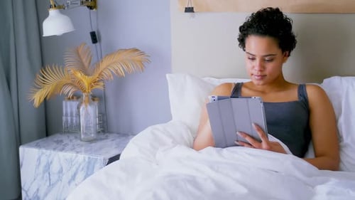 Woman Relaxes in Bed with Tablet at Home