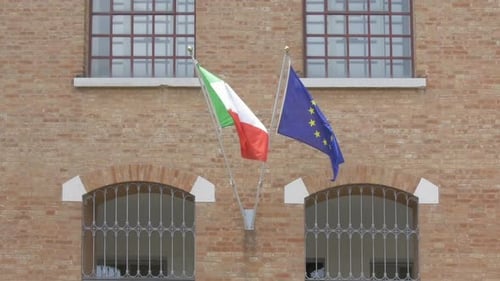 Italian and EU Flags Waving on Building Facade