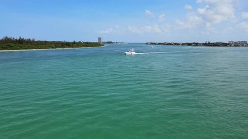 Flying low over an ocean bay as boats pass below the camera.