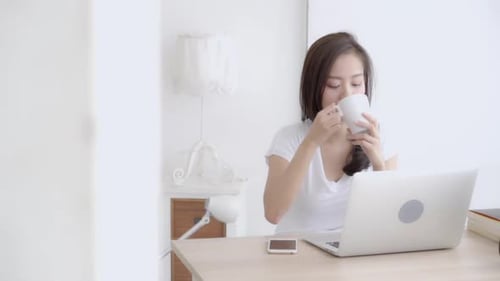 Young Woman Works on Laptop at Home with Coffee