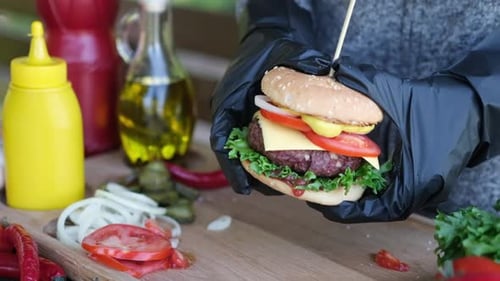 Close Up Shot Of A Female Hand Holding A Cheeseburger Outdoors