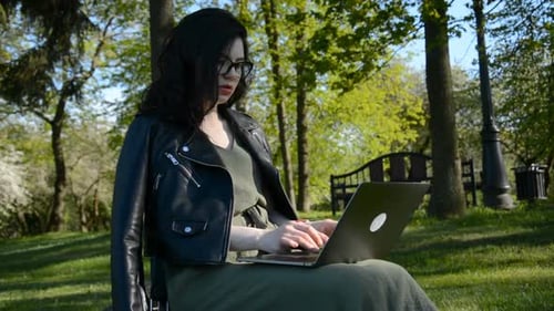 Outdoors Successful European Caucasian Woman Freelancer Sitting on the Grass a Summer Park and Using