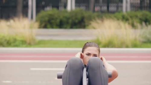 Junge Frau macht Fitnessübungen auf Trainingsgelände im Sommerpark