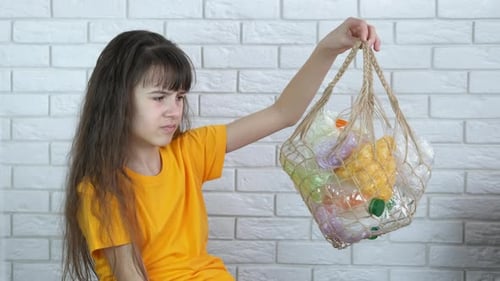 Child Holds Bag of Plastic Bottles with Disgust