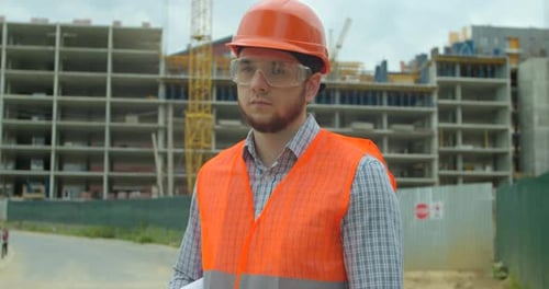 Portrait of an Architect or Builder in Hard Hat Standing in Front of Building Under Construction