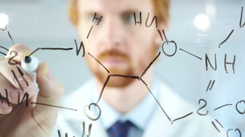 Un scientifique écrit une formule chimique sur du verre transparent