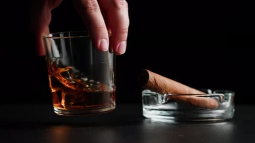 Whiskey with ice next to a cigar