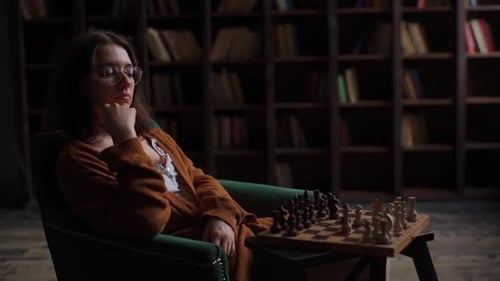 Portrait of Focused Intelligent Female Chess Player Wearing Glasses Making Move in Chess Game