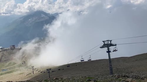 Clouds Enveloping Modern Ropeway with Benches in Amazing Mountainous Terrain