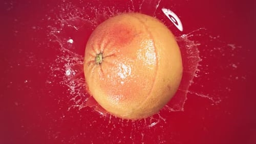 Grapefruit Splashes Into Red Liquid
