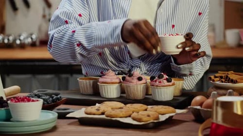 Woman Decorating Cupcakes with Sprinkles in Kitchen