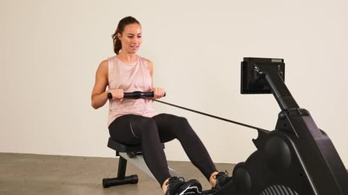 Woman Using Rowing Machine for Exercise in Gym
