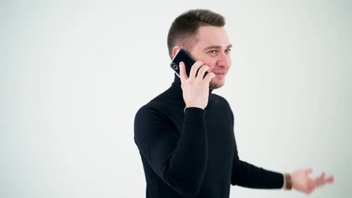 Hombre sonriente camina y habla por teléfono sobre fondo blanco.