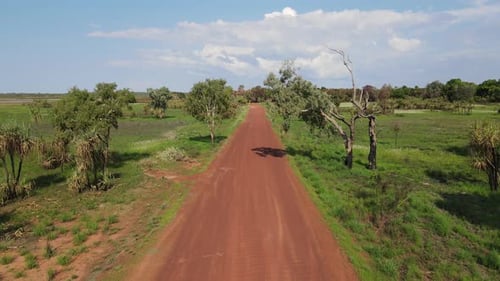 Low moving drone shot of Long Straight Red Road and Green Bushland near Holmes Jungle Nature Park, D