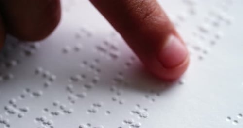 Estudante lendo um livro em braille em sala de aula na escola