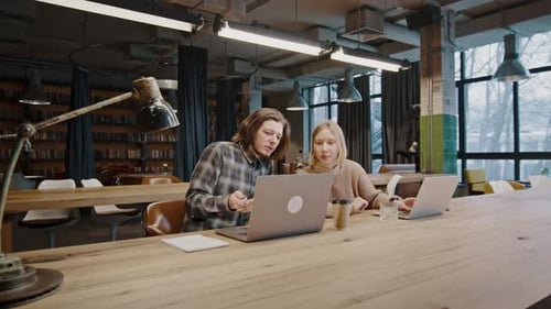 Young Adults Collaborating at Laptops in Urban Workplace