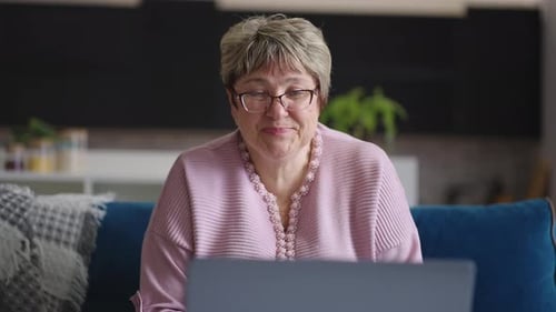 Smiling Woman Video Chatting on Laptop at Home