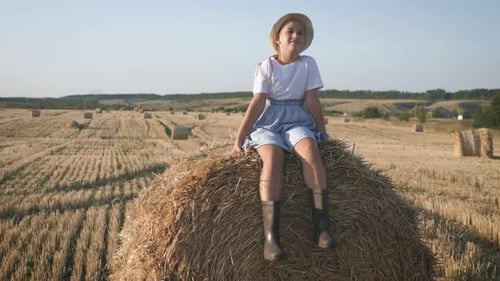 Pretty Girl in Blue Dress Walks in a Field with Haystacks