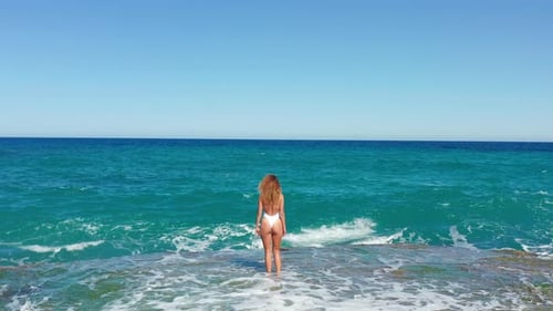 Young Woman in Bikini on Sea Shore and Splashing Water Waves Aerial Landscape. Beautiful Woman on