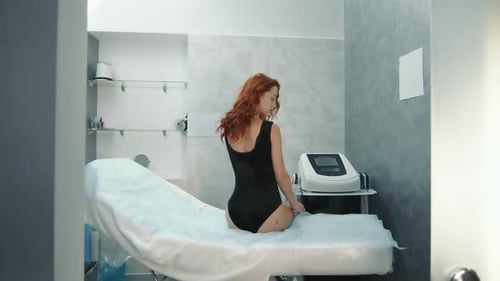 Woman Sits on Examination Table in Medical Clinic