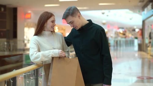 Portrait of Cheerful Young Couple Walking Inside Shopping Mall Showing Purchases in Bags Rejoicing