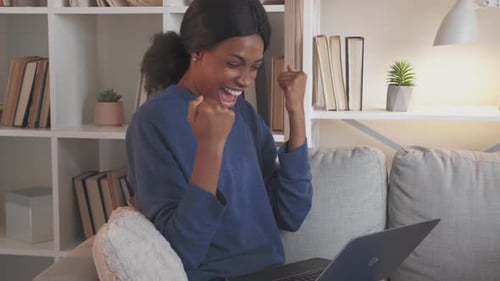 Woman Cheers While Using Laptop at Home