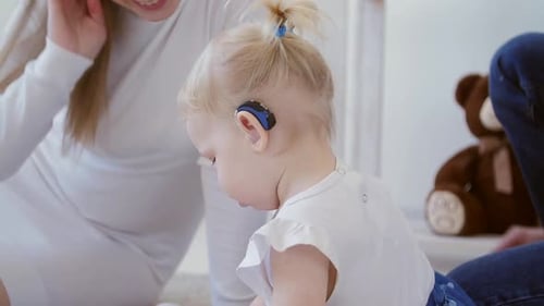 Blonde Child with Hearing Aid Playing with Family
