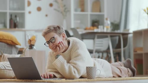 Woman Lies on Floor Using Laptop at Home