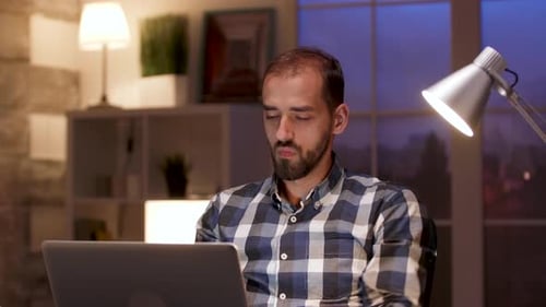 Bearded Businessman Stretching While Working on Laptop