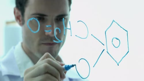 Scientist Writes Chemical Formulas on Clear Board