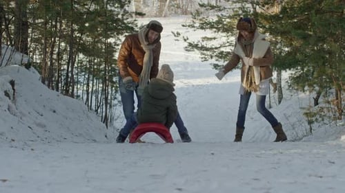 Casal pegando criança andando de trenó ladeira abaixo