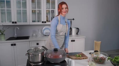 Woman Slicing Cucumber for Salad in Kitchen