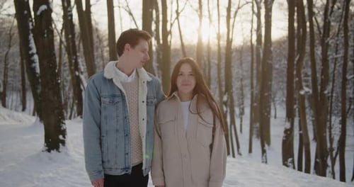 Happy Young Beautiful Couple Spend Time in Sunny Winter Forest Together