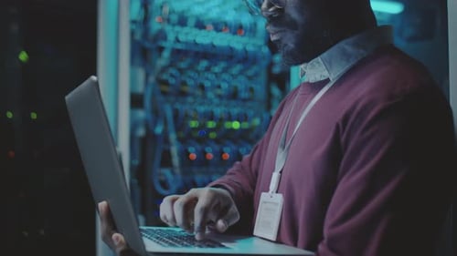 Man Working on Laptop in Server Room