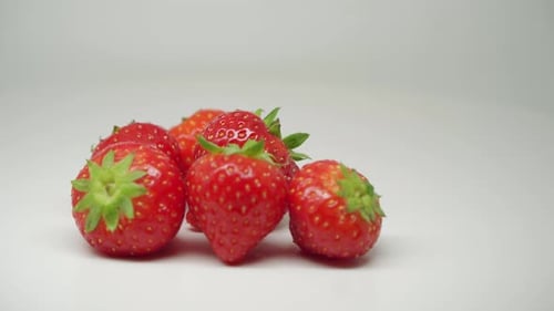 Six Red Strawberries Rotating On The Table With Pure White Background - Close Up Shot