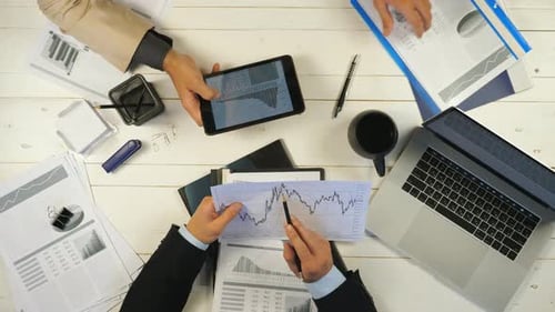Männliche Hände zweier erfolgreicher Geschäftspartner, die Grafiken untersuchen und Finanzberichte diskutieren in