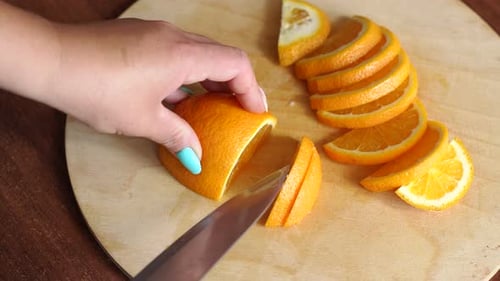 Closeup Girl schneidet eine reife saftige Orange auf einem Holzbrett