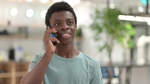 Young Adult Smiling While Talking on Phone Indoors